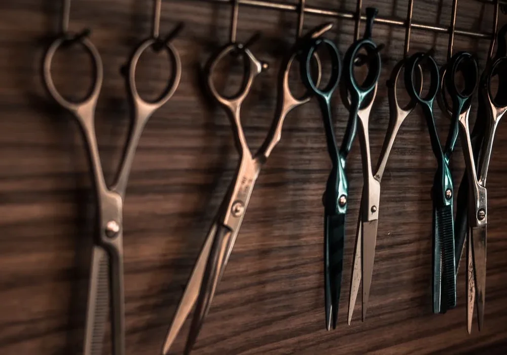 Ciseaux de coiffure alignés sur un plan de travail en bois au salon Chez Rachid